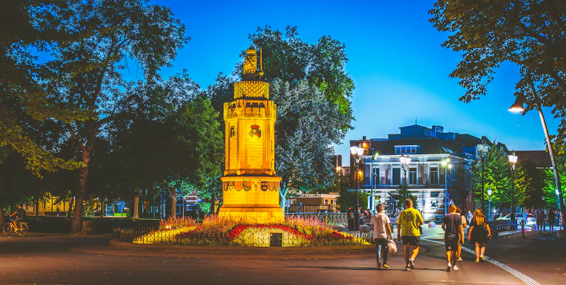 People walk past a monument at dusk