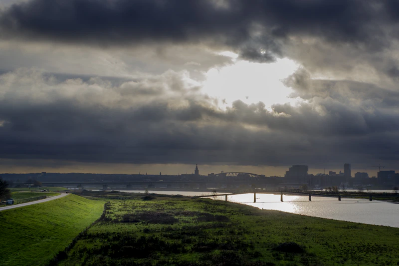 Stormy sky over a calm river and distant city.